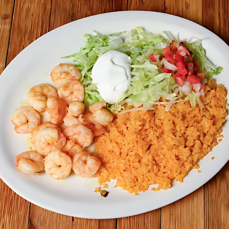A Tequila Mexican Restaurant plate with shrimp, orange rice, shredded lettuce, sour cream, and pico de gallo.